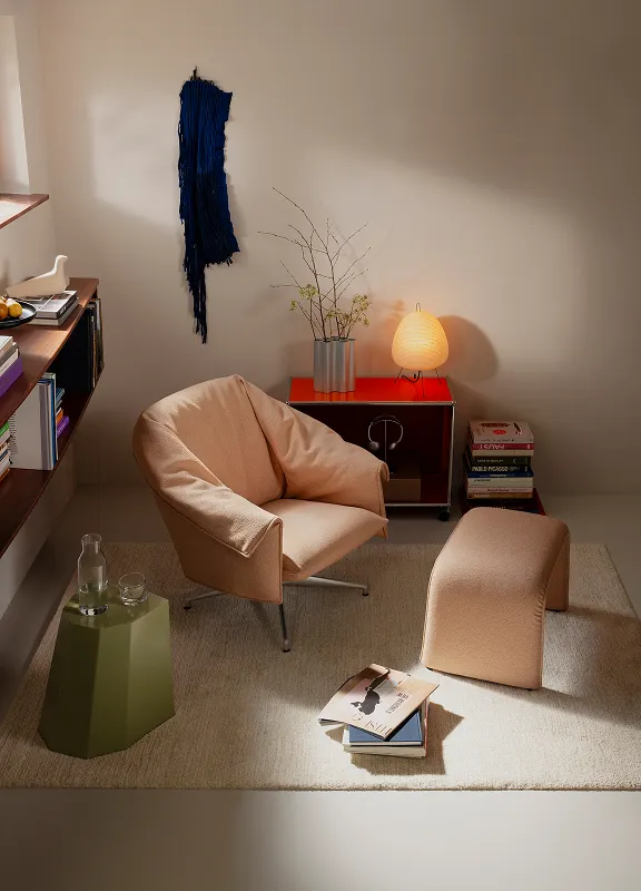 Der Loungechair Bascule in Apricot mit passendem Hocker in einem stilvollen Wohnzimmer.